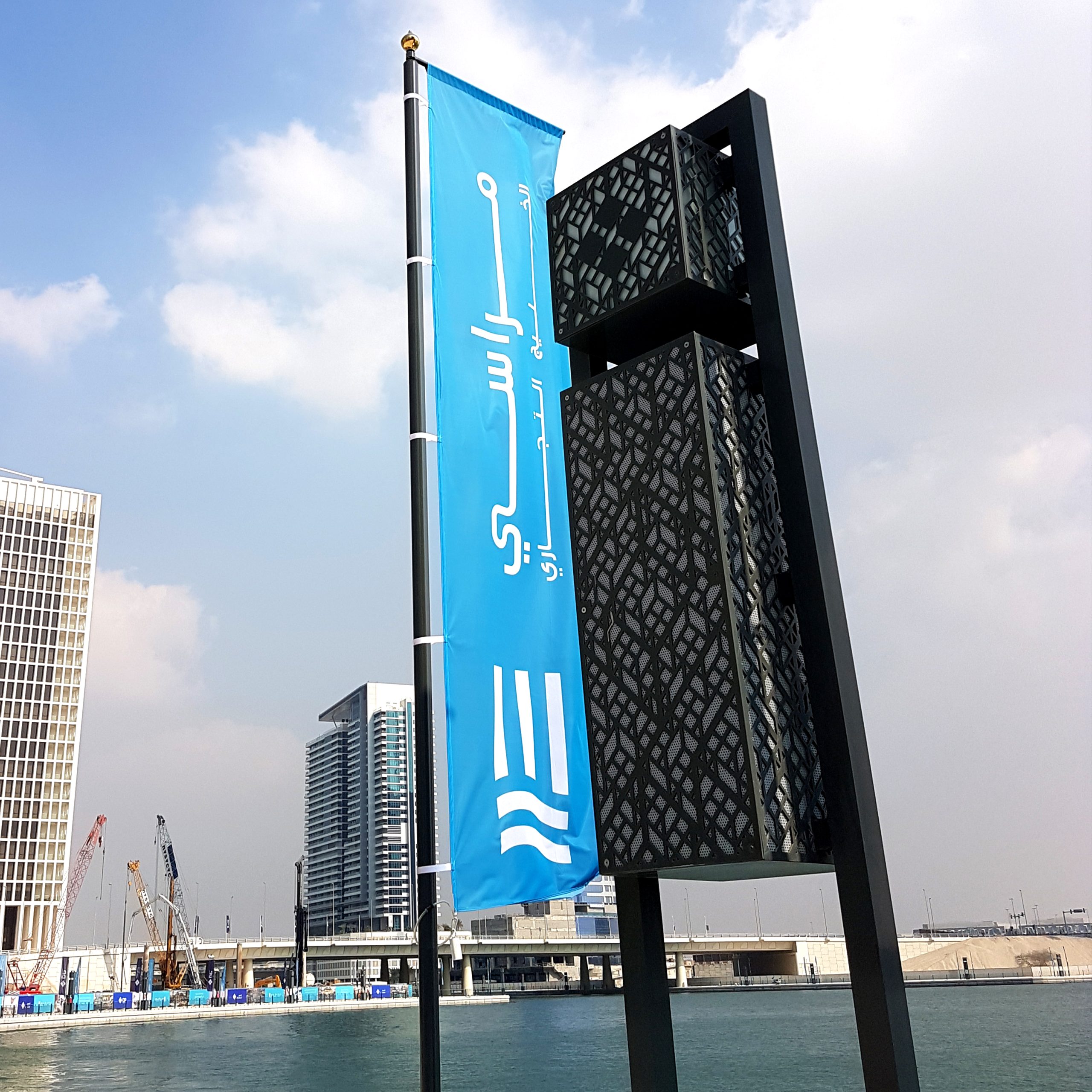  A blue flag featuring Arabic writing is displayed on a tall pole against a clear sky