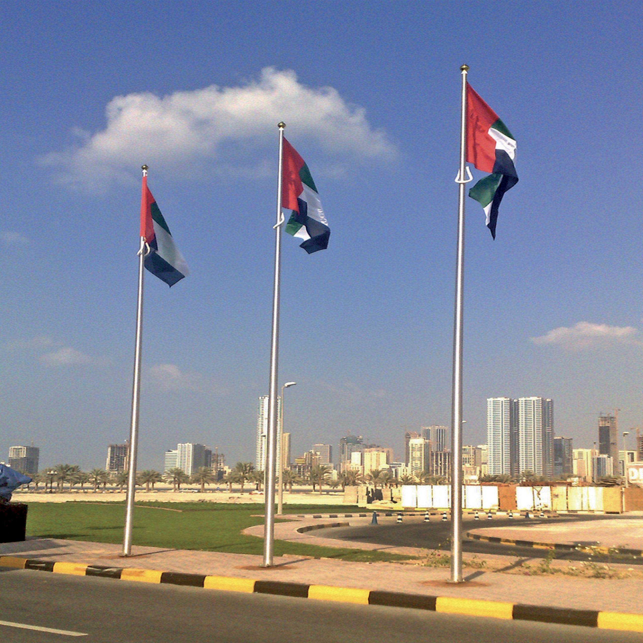 A row of colorful flags fluttering on a tall pole against a clear blue sky