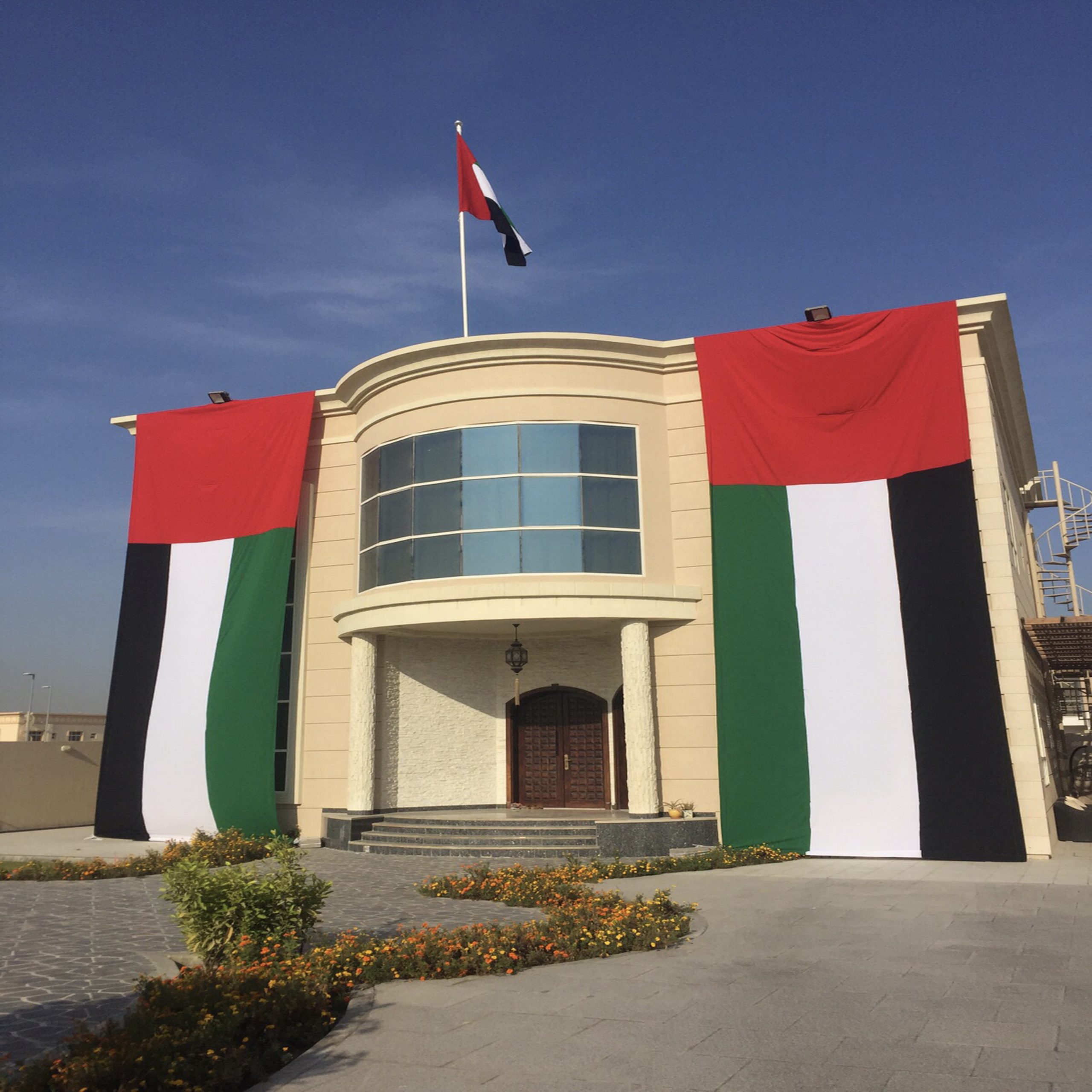 A white building stands prominently against a clear blue sky, showcasing its clean and modern architectural design.